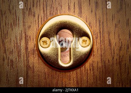 Close up of a keyhole and eye peeping through Stock Photo