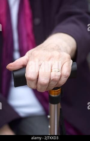 Close up of elderly womans hand resting on her walking stick Stock Photo