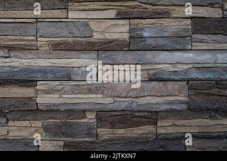 Artificial stone imitation brick wall with the look of pressed together flat stonesof different colour to create an interesting texture. Stock Photo