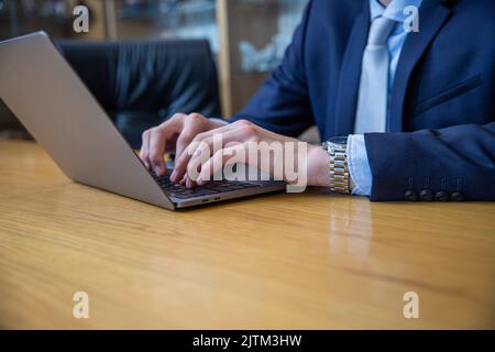 Closeup of the hands of a businessman typing on his laptop keyboard with copy space underneath Stock Photo
