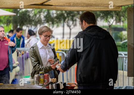 LONDON - May 20, 2022: Woman uses smartphone to make contactless payment for street food Stock Photo