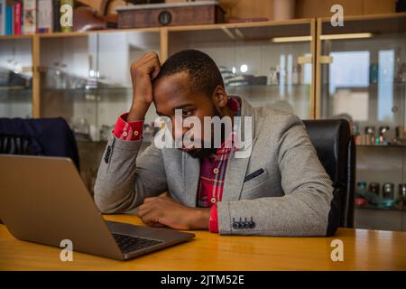 A businessman is sad and angry while he is in the office looking at his laptop screen. Stock Photo