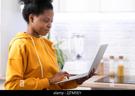 Happy attractive african american girl working office work remotely from home Black woman using laptop computer Distance learning online education and Stock Photo