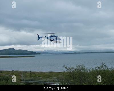 Staloluokta, Norrbotten, Sweden, Agust 11, 2021: Blue Fiskeflyg helicopter with tourist and supplies landing at sami village Staloluokta at Virihaure Stock Photo