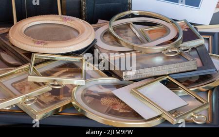 Multiple picture frames to fill with photos. Here is a pile of unused small picture frames including glass, rims, framework, mats, and a few photos. Stock Photo
