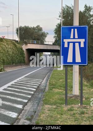 Vertical shot on the entrance driveway via a tunnel of a Belgian the highway with a white lined blue road sign Stock Photo