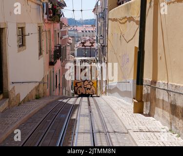 Graffiti covered Tram aka Streetcar aka Trolley in the Baixa-Chiado area of Lisbon with the River Tagus in the distance. Portugal. Stock Photo