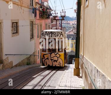 Graffiti covered Tram aka Streetcar aka Trolley in the Baixa-Chiado area of Lisbon with the River Tagus in the distance. Portugal. Stock Photo