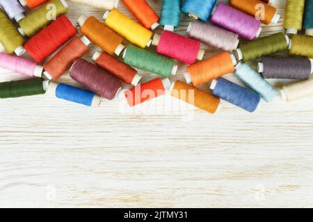 Scattering of various colors sewing threads on white wooden background. Flat lay, top view. Stock Photo
