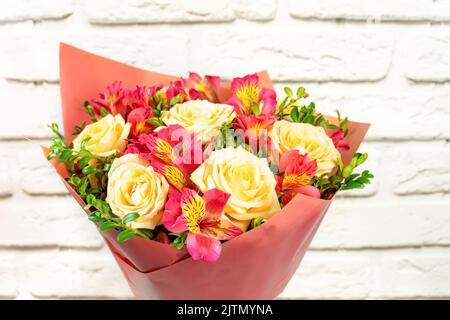 Bouquet of beautiful roses and alstroemeria on white brick background. Fresh, lush bouquet of colorful flowers for wedding, valenitnes day, mother day Stock Photo