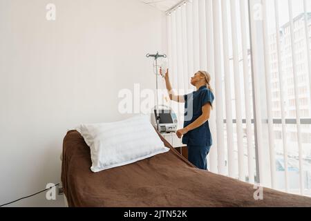 Professional nurse preparing an intravenous drip before procedure in hospital ward Stock Photo