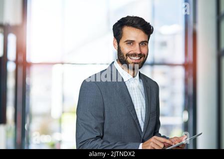 Ive integrated some great business apps into my workday. Portrait of a happy young businessman using a digital tablet in a modern office. Stock Photo
