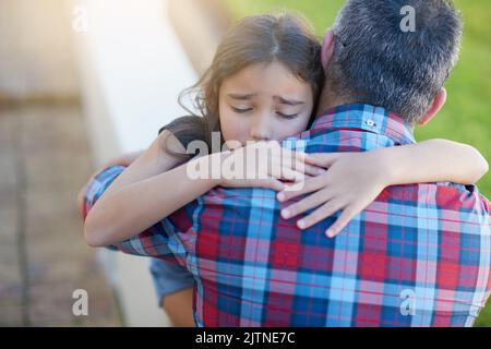 Daddys hugs make everything better. a sad little girl being consoled by her father at home. Stock Photo