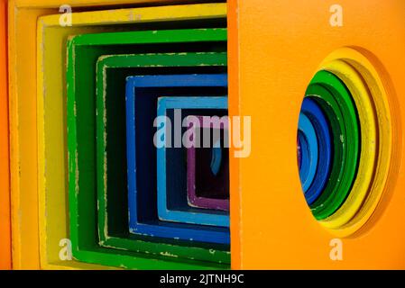 Multicolored children's wooden toy blocks with concentric circles cut into the side, stepped down in size for each color, orange is biggest, purple sm Stock Photo