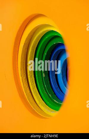 Multicolored children's wooden toy blocks with concentric circles cut into the side, stepped down in size for each color, orange is biggest, purple sm Stock Photo