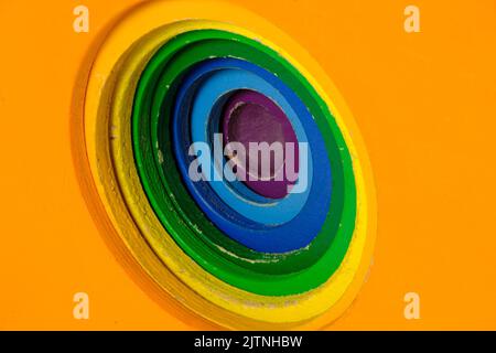 Multicolored children's wooden toy blocks with concentric circles cut into the side, stepped down in size for each color, orange is biggest, purple sm Stock Photo