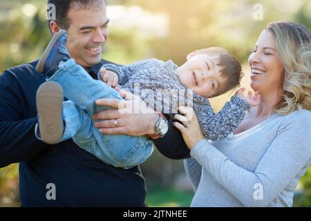 His laugh is just the cutest. parents bonding with their little boy outside. Stock Photo