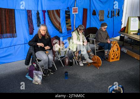 BELLEVUE, WASHINGTON, USA – APRIL 30, 2022: Kelsey Creek Farm Park heritage event, women demonstrating spinning wool into yarn Stock Photo