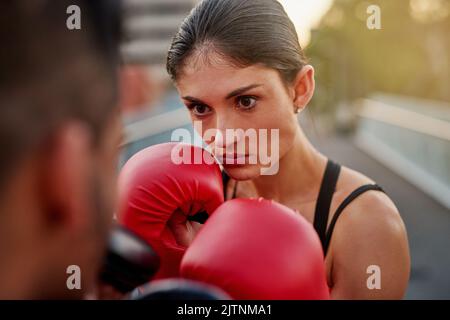 Focused on the fight. a young couple going through some kickboxing routines outdoors on a bridge. Stock Photo