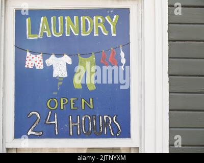KETCHIkAN, Alaska USA - JULY 25; 2008 Hand painted sign advertising home laundry business on window close up blue background Stock Photo