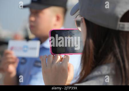 DONGYING, CHINA - SEPTEMBER 1, 2022 - Policemen officers explain how to use a small program for vessel filing to fishermen with the help of a live med Stock Photo