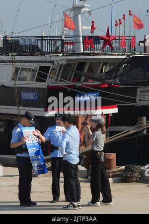 DONGYING, CHINA - SEPTEMBER 1, 2022 - Policemen officers explain how to use a small program for vessel filing to fishermen with the help of a live med Stock Photo