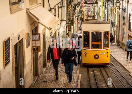 Lisbon, Portugal - March 29, 2018: People and yellow funicular tram tram, symbol of Lisbon and downtown street perspective Stock Photo