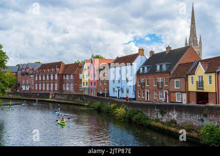 Colourful houses on Quayside in Norwich, North Norfolk, UK along the River Wensum with paddleboarders sailing passed Stock Photo