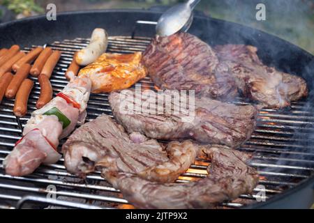 large beef steaks and sausages on charcoal grill Stock Photo