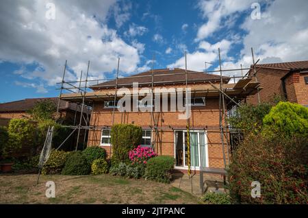 1990's red brick detached house with scaffolding erected to enable roof repairs to be carried out; Wootton, Northampton, UK Stock Photo