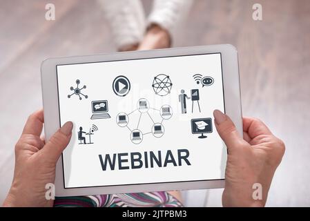 Webinar concept shown on a tablet held by a woman Stock Photo