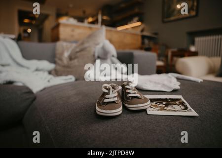 Mother to be places baby's ultrasound and shoes on the sofa  Stock Photo