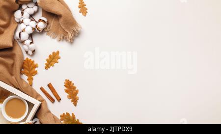 Autumn concept of comfort. Cashmere scarf, a cup of coffee with autumn oak leaves on a gray background. Stock Photo