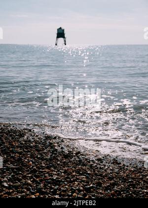 The Dovercourt Victorian Low Lighthouse and summer pebble beach and sea at  Harwich in Essex England UK - summer lighthouse sea coast Stock Photo