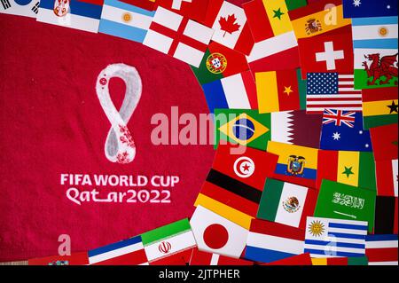 DOHA, QATAR, AUGUST 30, 2022: Flags of all 32 teams participating on FIFA World Cup Qater 2022. Official Logo of Soccer tournament on red background Stock Photo