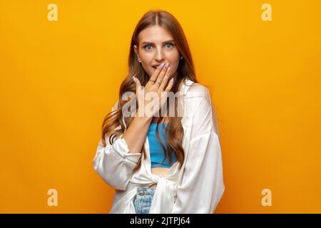 Photo of beautiful woman holding hands near mouth against yellow background Stock Photo