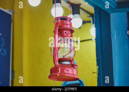 A bright red retro lantern hangs in an open cafe, as a decorative element, against a yellow wall. Stock Photo