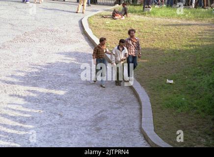 Bucharest, Romania, April 1990. A few months after the anti-communist revolution, sign of poverty and struggle were still seen anywhere. Here, an intoxicated man is helped by two others to walk. Stock Photo