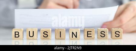 Woman manager studying documents near words business on wooden cubes closeup Stock Photo