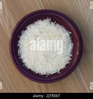 Finely Grated Parmesan Cheese in a Small Purple Bowl Stock Photo