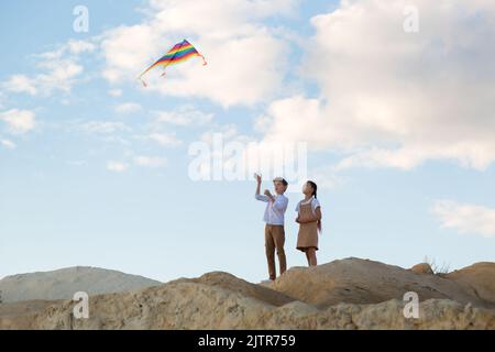 Brother and sister fly a kite into the sky high mountain. Stock Photo