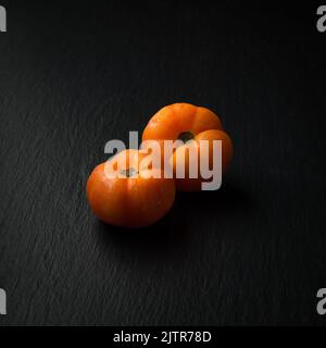 fresh tomatoes, edible berries isolated on slate black surface, copy space Stock Photo