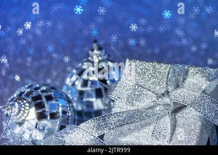 Christmas blue background with free place for text. Gift box close-up with shiny bow and balls on an abstract background with glittering snowflakes bo Stock Photo