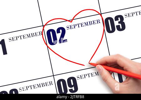 2nd day of September. A woman's hand drawing a red heart shape on the calendar date of 2 September . Heart as a symbol of love. Autumn month. Day of t Stock Photo