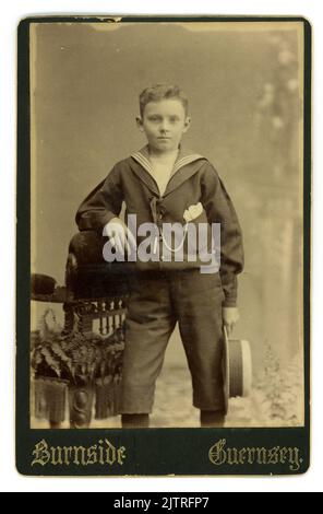 Original Victorian studio portrait cabinet card of good looking young lad about 8 or 9 years old, wearing a sailor suit fashionable at the time. From the studio James Burnside, St Peter Port, Guernsey, Channel Isles. Circa 1890's Stock Photo