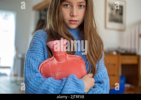 little girl holding hot water bottle against her . Stock Photo