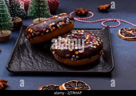 Pastries concept. Donuts with chocolate glaze with sprinkles, on a dark concrete table. Sweet food for a breakfast Stock Photo