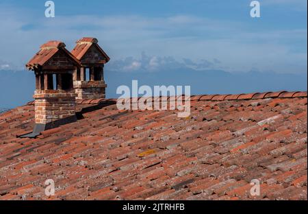 Roofs with tiles and two brick chimneys, blue sky and clouds Stock Photo