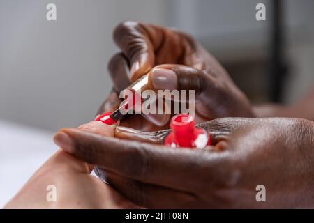 Black woman applies nail rouge. Stock Photo