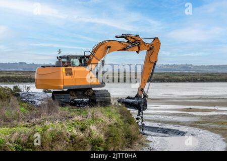 A backhoe clears a ditch Stock Photo